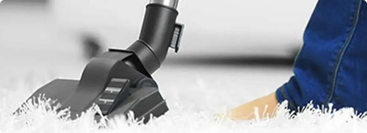 Close-up of a professional vacuuming a white carpet in Harwood.